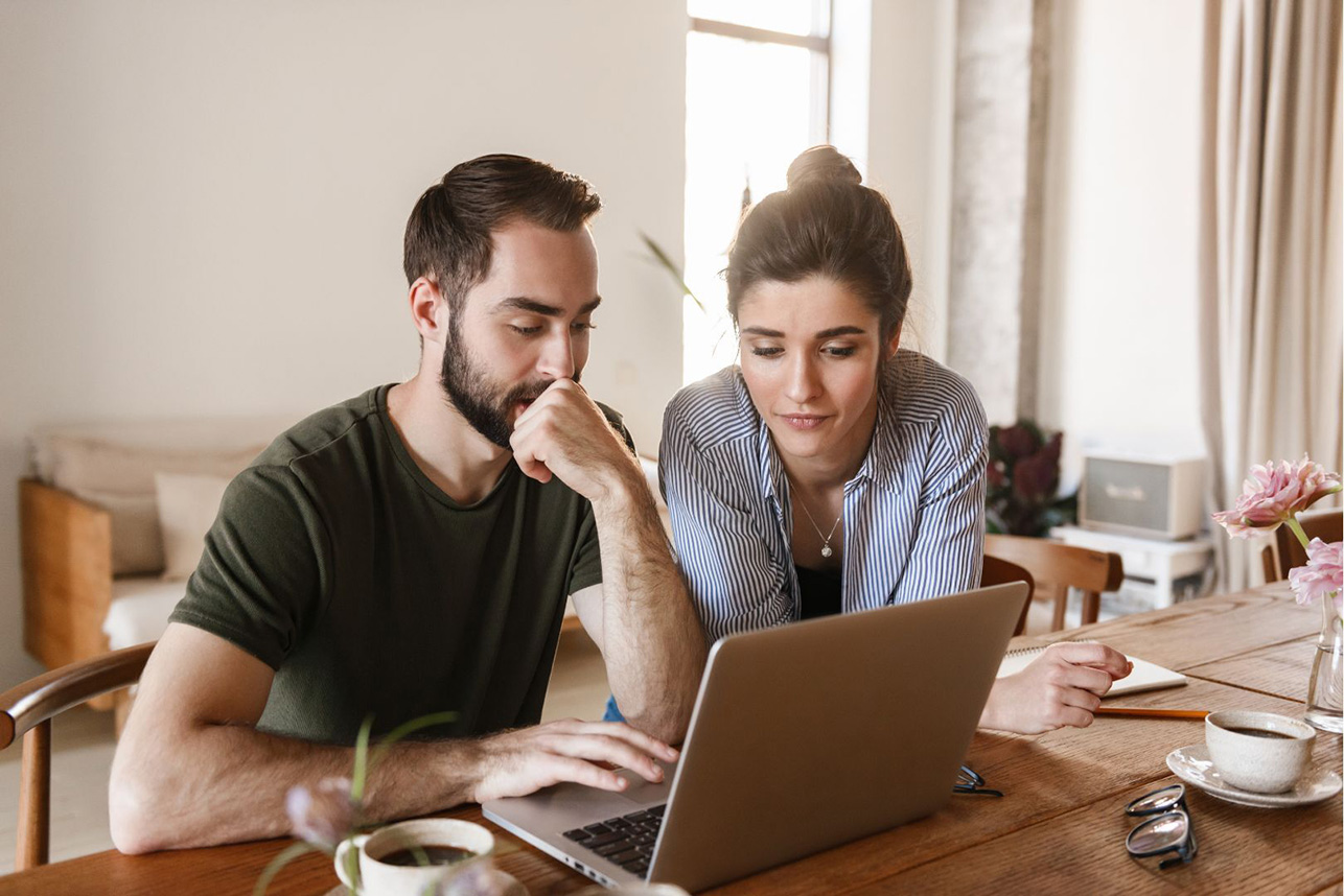 A man and a woman looking at a laptop together at home